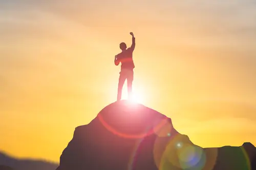 Business person at summit of mountain